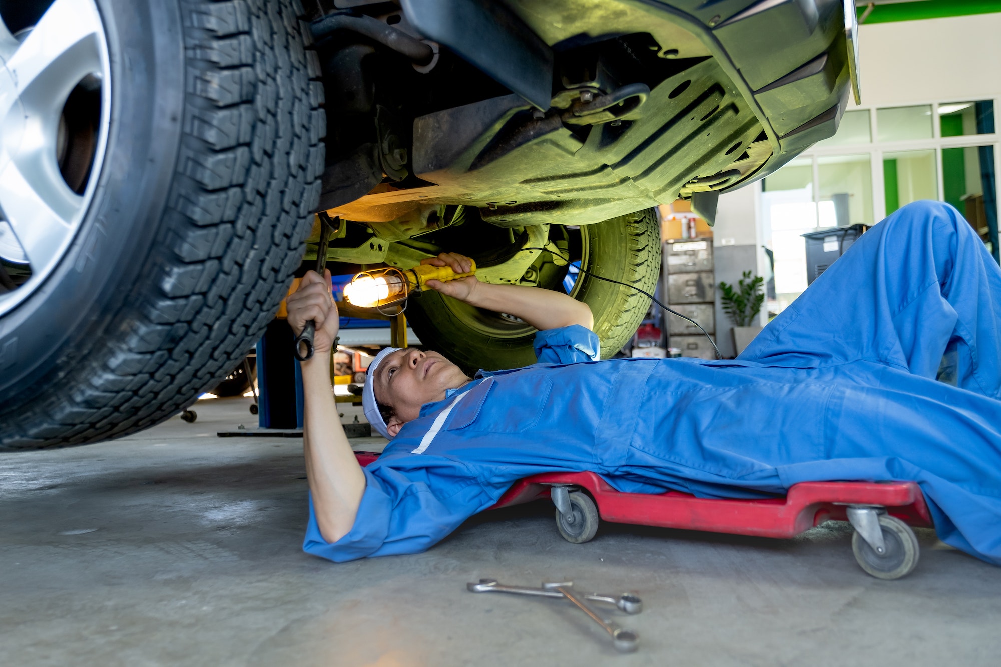 technician-or-garage-worker-lie-down-under-the-car-and-use-lantern-to-guide-for-fix-the-problem.jpg